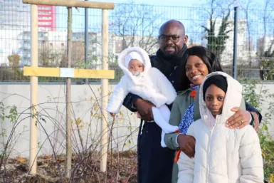 Une famille souriante devant un arbre portant le prénom du bébé