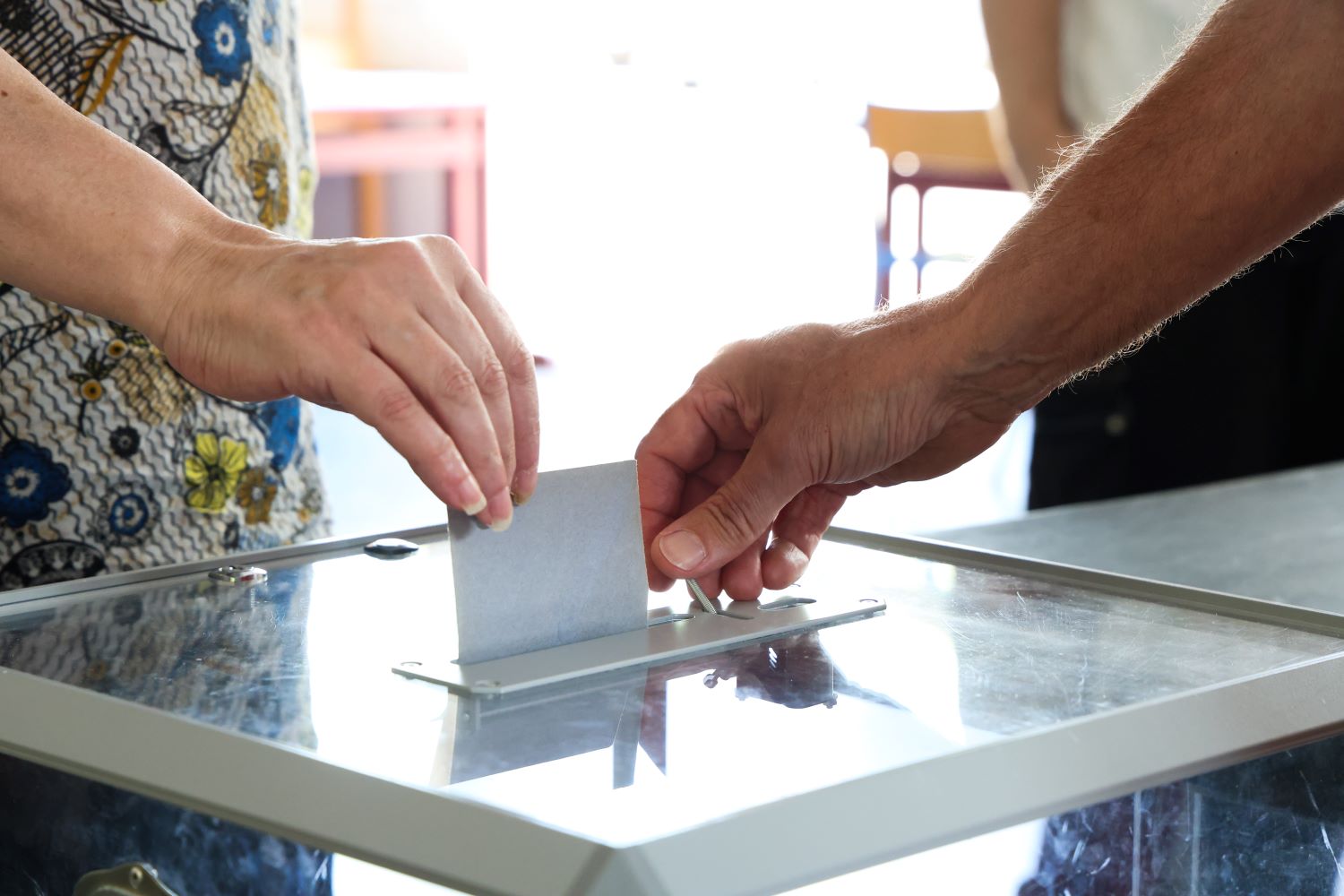 Une main glisse un bulletin de vote dans une urne