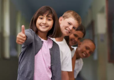 Un groupe d'enfants. Au premier rang, une jeune fille brune lève le pouce.